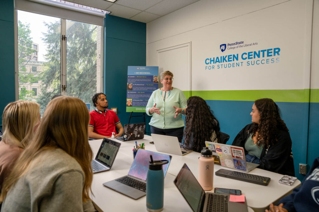 Patty Klug, director of the Chaiken Center for Student Success, presents to a group of students with the Chaiken Center word mark visible on the wall next to her.